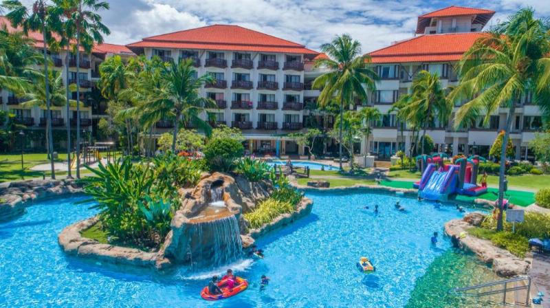 Một người phụ nữ đang mỉm cười thư giãn trong bồn tắm bùn tại I-Resort, xung quanh là cây xanh.